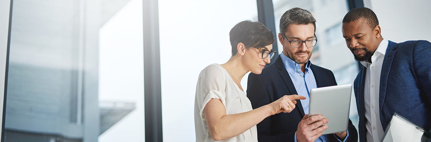 Three colleagues looking at a tablet together.