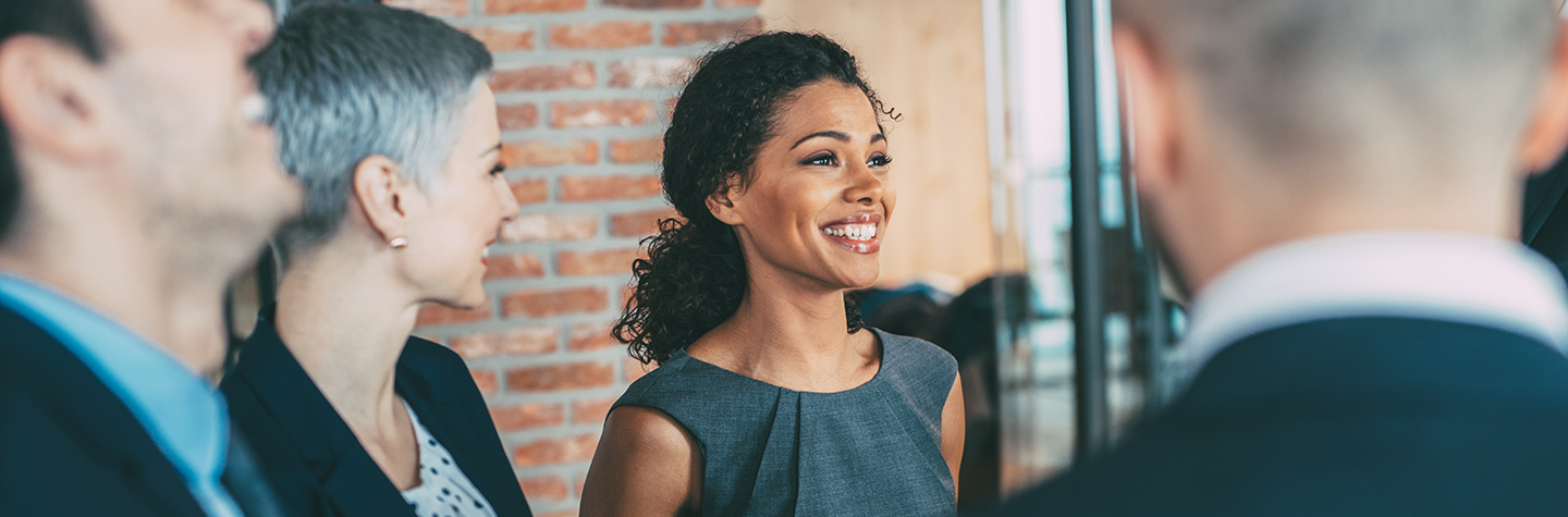 Woman smiling as she talks to other people in a small group.