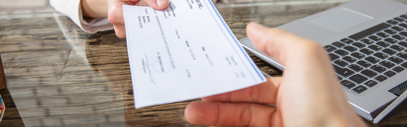 A hand holding a cheque handing it to another hand