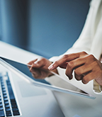 A hand typing on a tablet.